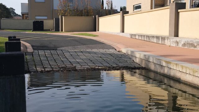 Concrete boat ramp with paved cobblestone or vehicle access point leading into a suburban water in a residential estate. Melbourne Australia.