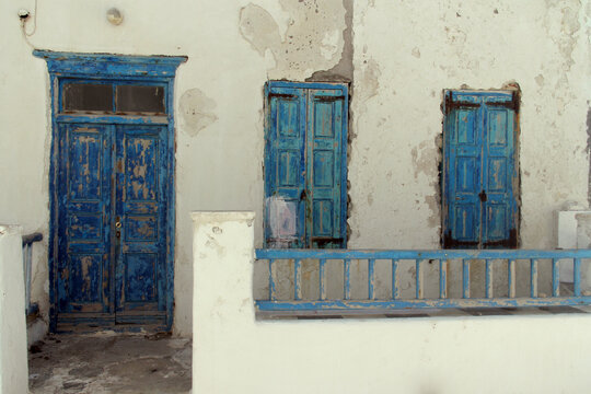 Traditional blue wooden doors on a white stone wall of an ancient building in Chania, Crete, Greece.