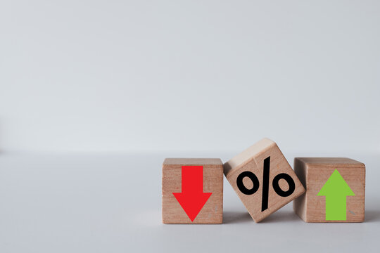 Wooden blocks with a percentage sign, green up arrow, and red down arrow on a white background.Financial market fluctuation, interest rate,inflation,economic growth,investment with copy space.