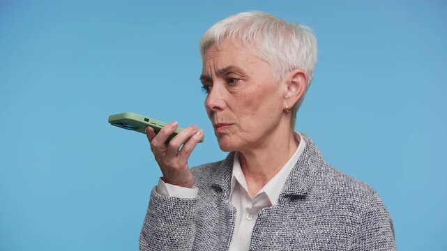 Mature Woman Using Smartphone Voice Command on Blue Background