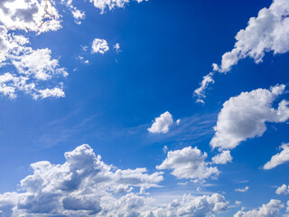 Fluffy white clouds drifting across blue sky © IbragimovN