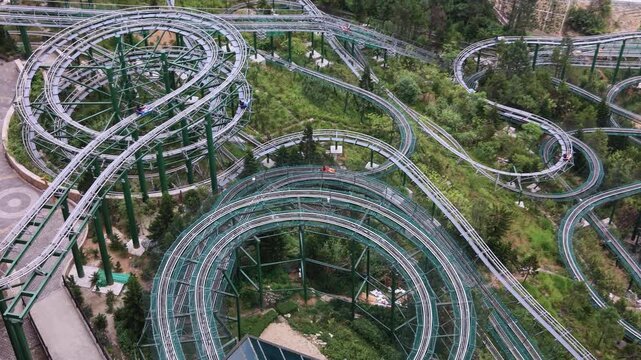 Ba Na Hills SunWorld amusement park features a winding roller coaster track and colorful cable cars over lush green forested hills in Vietnam.
