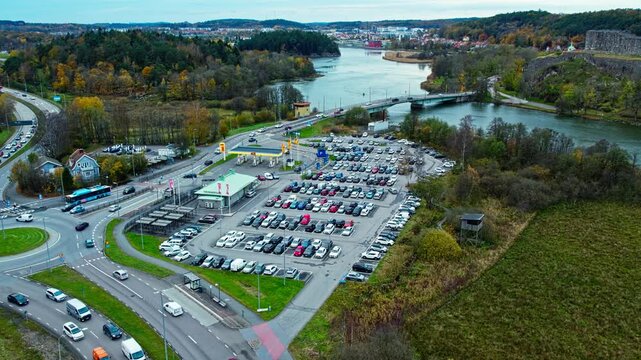 Aerial drone view of parked cars at Vikingagrillen near Bohus Fortress in Kungalv Sweden. Restaurant parking area with bridge river roads and surrounding buildings viewed from above