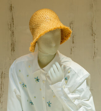 Summer Mannequin in a Woven Straw Bucket Hat with an Embroidered White Cotton Fashion Shirt.