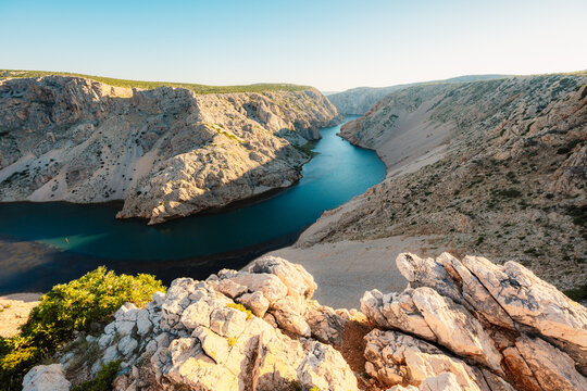 View of the Zrmanja River Canyon in Croatia, with winding turquoise waters cutting through limestone cliffs. A scenic natural wonder popular for kayaking and hiking