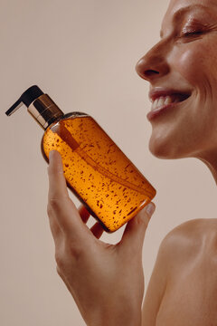 Smiling woman holding amber pump bottle of serum