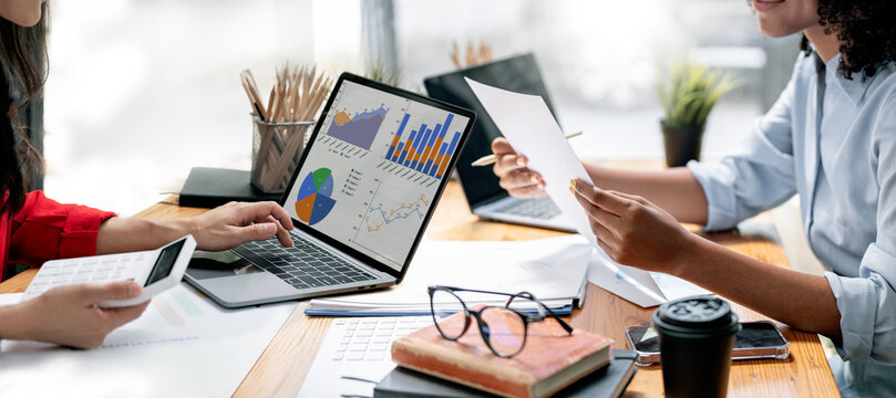 Business colleagues analyzing financial charts and data on laptop
