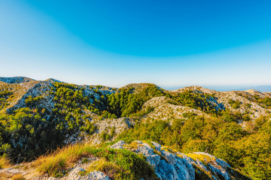 Rugged karst landscape of Biokovo Nature Park with white limestone rocks and sparse mediterranean vegetation, Dalmatia, Croatia.