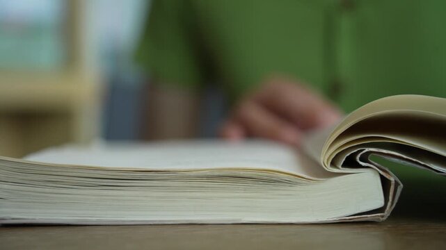 Close-up of female hands turning page book. Unrecognizable Person's Hand reading a book and holding fingers along the lines. Concept for reading, studying, research, education.