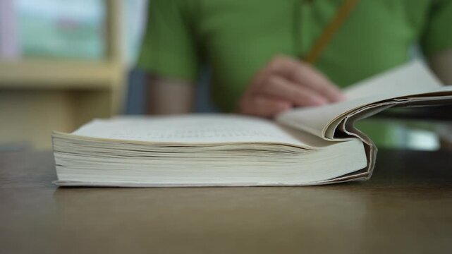 Close-up of female hands turning page book. Unrecognizable Person's Hand reading a book and holding fingers along the lines. Concept for reading, studying, research, education.