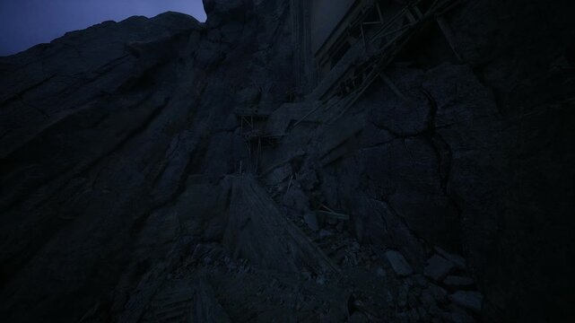 Narrow cliff path winding between timber rafters, steep drop and rugged rock faces dominate frame, intimate low light and deep shadows emphasize danger