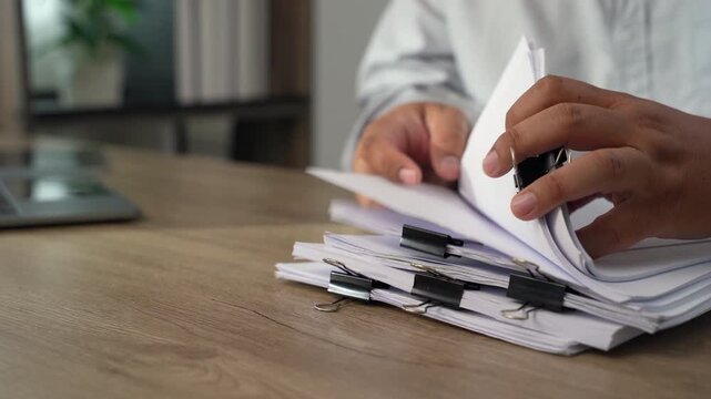 business man  sorting thick paper Document management system  on a wooden desk, showing an organized filing process for office records and document management workflow.