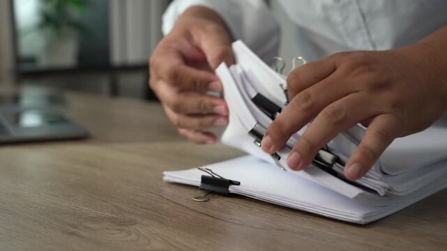 business man  sorting thick paper Document management system  on a wooden desk, showing an organized filing process for office records and document management workflow.
