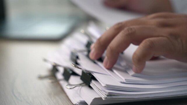 business man  sorting thick paper Document management system  on a wooden desk, showing an organized filing process for office records and document management workflow.