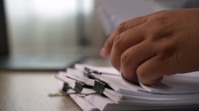 business man  sorting thick paper Document management system  on a wooden desk, showing an organized filing process for office records and document management workflow.