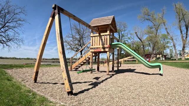 an empty winter playground by the lake, with swings swaying in the wind