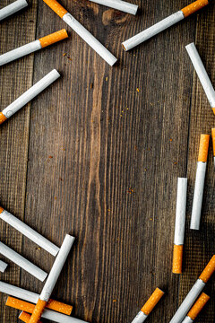 Tobacco. Scattered cigarettes on dark wooden background top view copy space