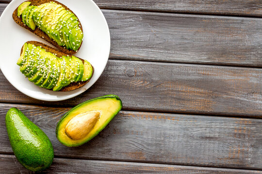 Healthy breakfast. Avocado toast on dark wooden background top view copy space