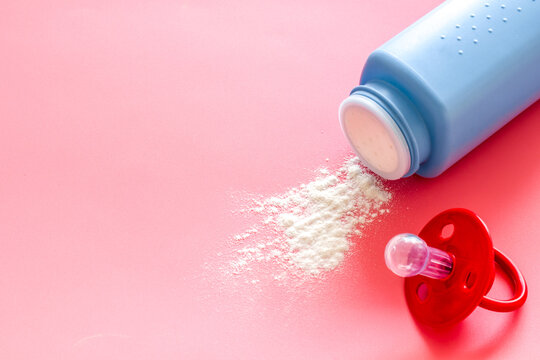 Baby talcum powder for delicate skin care near pacifier on pink background copy space