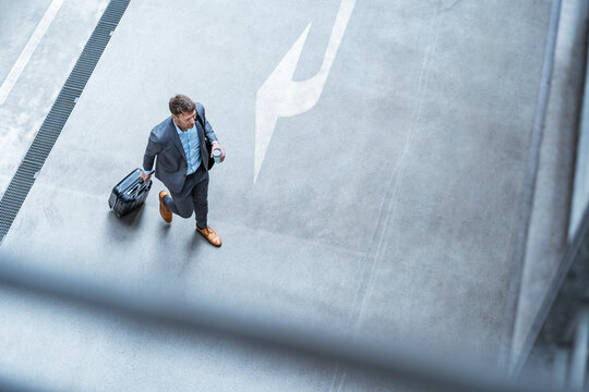 Top view of businessman walking with baggage and takeaway coffee