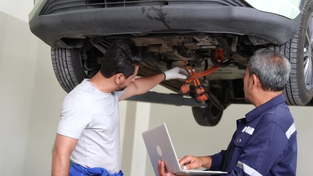 Team of automotive technicians working together on vehicle repairs in a contemporary workshop setting
