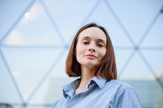 Confident businesswoman stands outdoors near modern office building