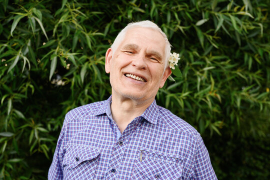 A cheerful man with a flower enjoys nature outdoors