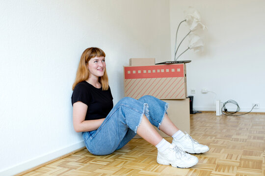 Smiling young student sitting on the floor during move