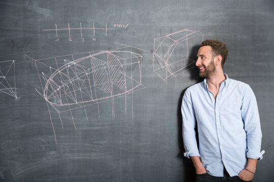 Young man looking at drawing at blackboard