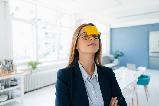 Young businesswman with yellow sticky note on her forehead