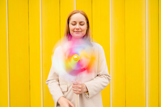 Businesswoman holding spinning pinwheel outdoors with optimism
