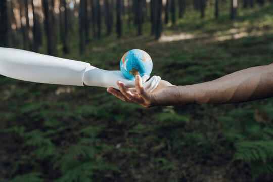 Man and robot holding earth globe together in forest