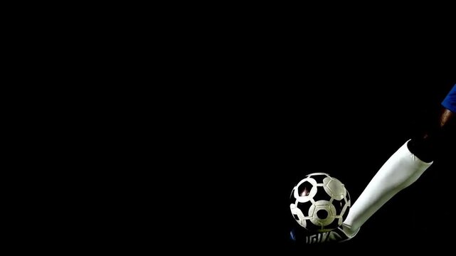 Professional soccer player foot juggling a ball on black background