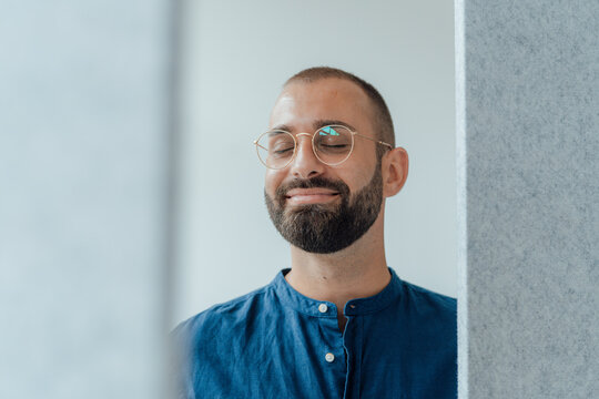 Smiling businessman with eyes closed at home office