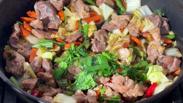Meat and vegetables stir-frying in pan for laghman stew preparation

