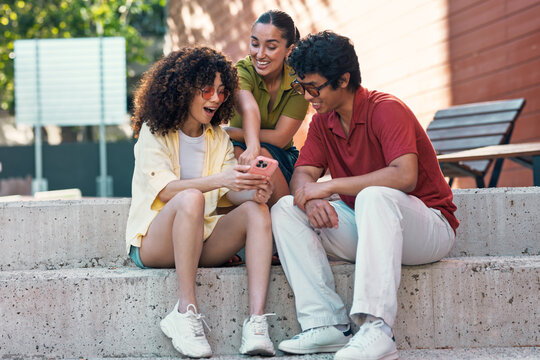 A group of friends looks at a smartphone outdoors