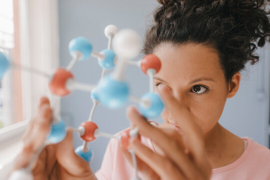 Female scientist holding molecule model, looking for solutions