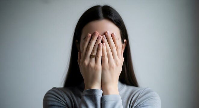 Woman covering face with hands feeling shame, sadness, or shy emotion