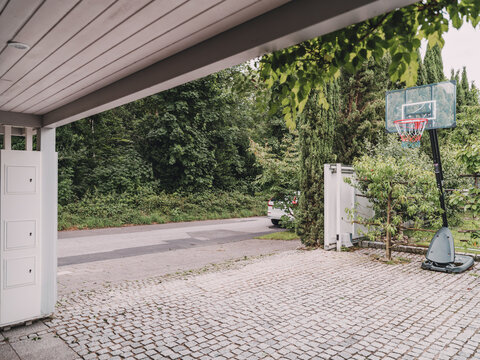 Empty cobblestone driveway with a basketball hoop outside a villa