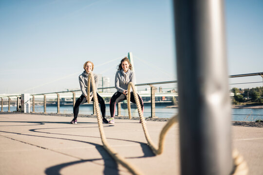 Friends training at the riverside, pulling rope