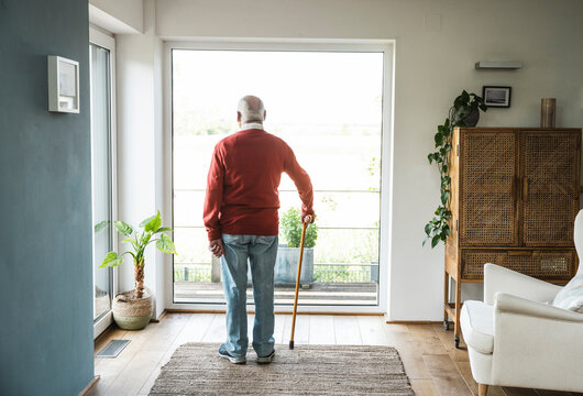Contemplative senior man standing in front of window