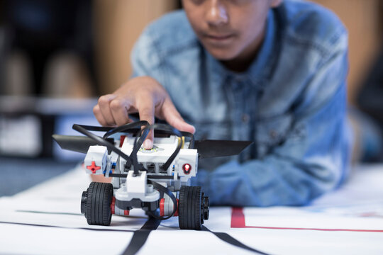 Schoolboy in robotics class testing vehicle on test track