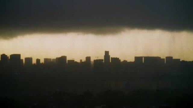 Dramatic and beautiful shot of dark clouds gathering over the modern cityscape, silhouetted against the sunrise, as monsoon rain showers over city skyline. Cinematic urban landscape of Mumbai, India