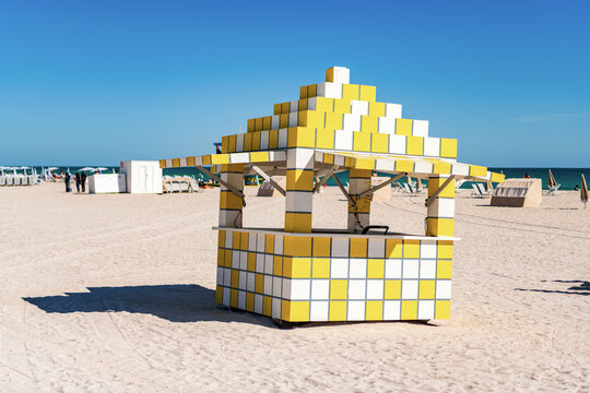 Yellow and white checkered beach hut. Towel stand in Miami, Florida. South beach touristic destination. Summer vacation on Miami beach. Cubic lifeguard tower. Beach kiosk architecture