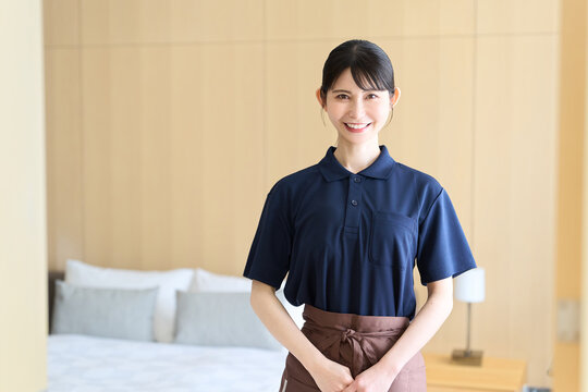 客室で笑顔で立つホテルの女性清掃員
