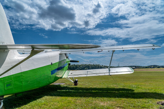Antonov an-2 biplane standing on green grass airfield under a blue sky