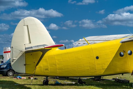 Classic yellow antonov an-2 biplane standing on grass, a blue sky with white clouds