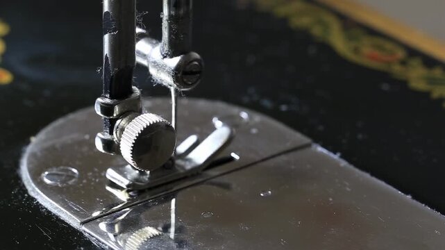 Close-up view of intricate mechanism of vintage sewing machine with needle moving up and down, highlighting presser foot and metal plate for fabric stitching and textile art