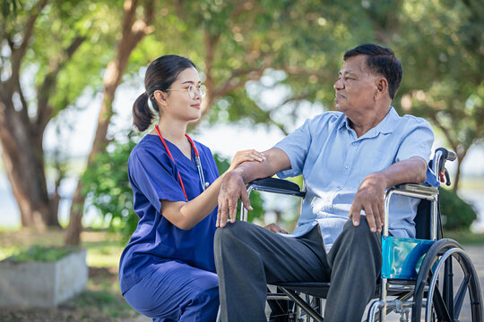 Female nurse caregiver male senior patient share A compassionate moment outdoors in park tranquil and supportive.