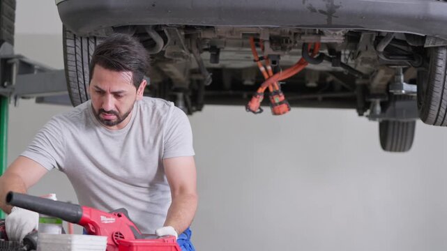 Expert technician conducting vehicle maintenance in a workshop surrounded by various tools and equipment